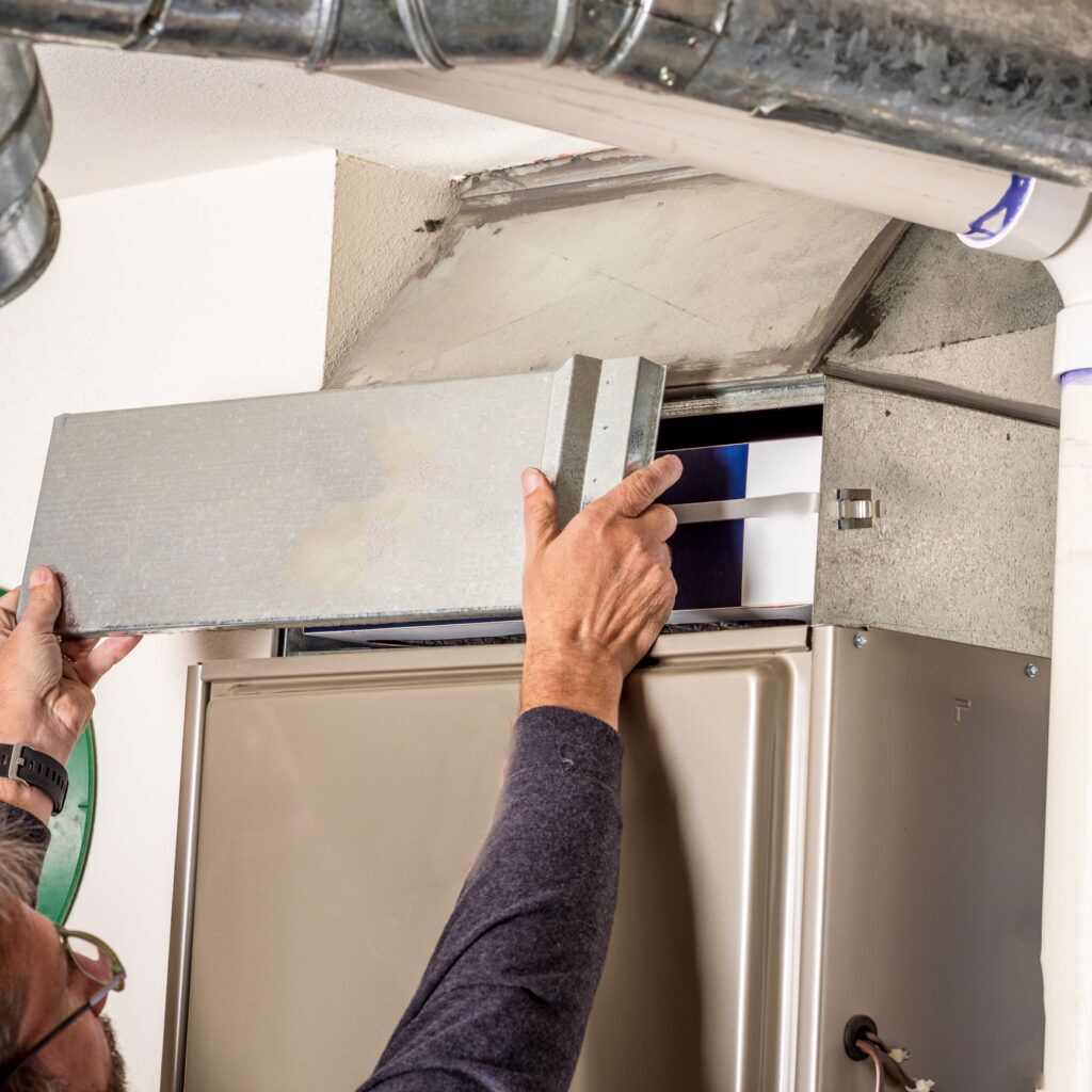 Technician removes furnace access panel for maintenance