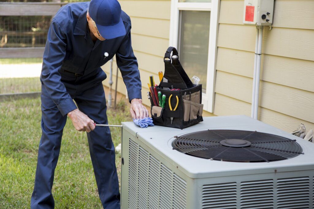 Senior adult air conditioner technician services outdoor unit.